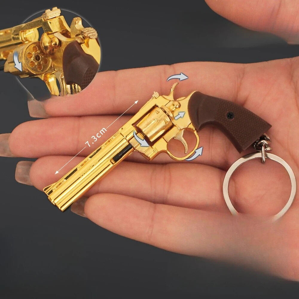 Gold-colored revolver keychain held in a hand with measurement details.