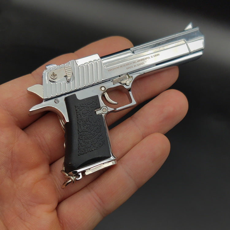 Metallic handgun model held in a hand against a dark background