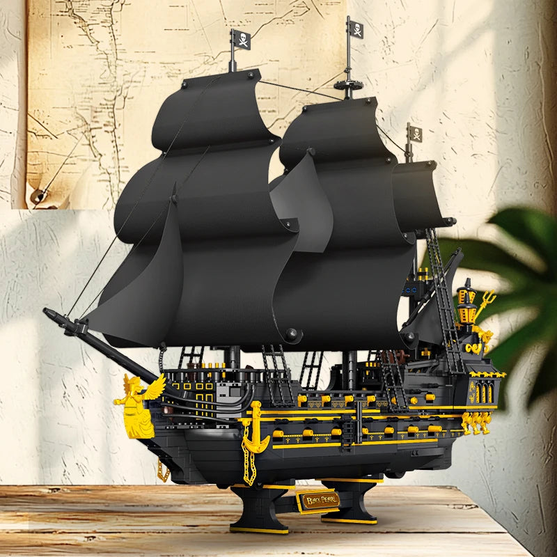 Model of a pirate ship with black sails and yellow details on a wooden platform.