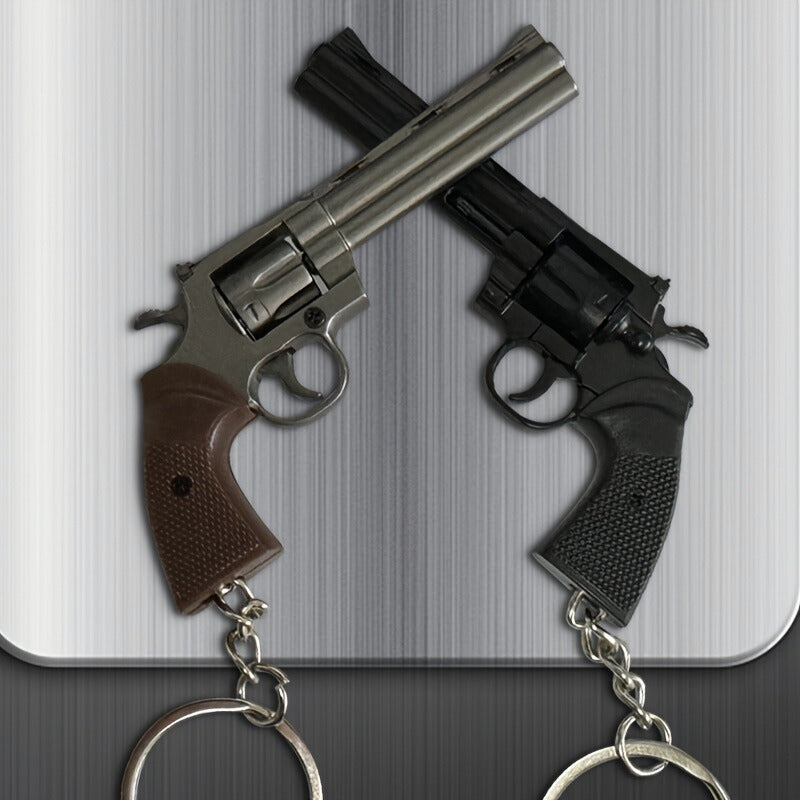 Two revolver keychains on a metallic surface