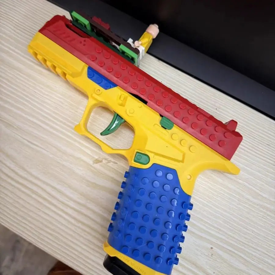 Colorful toy gun made of interlocking bricks on a wooden surface