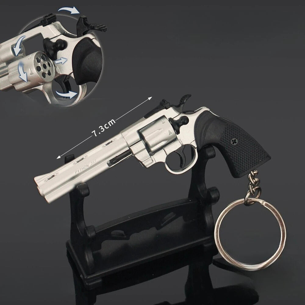 Revolver model on a stand with measurement details and a keychain attached, on a dark background.
